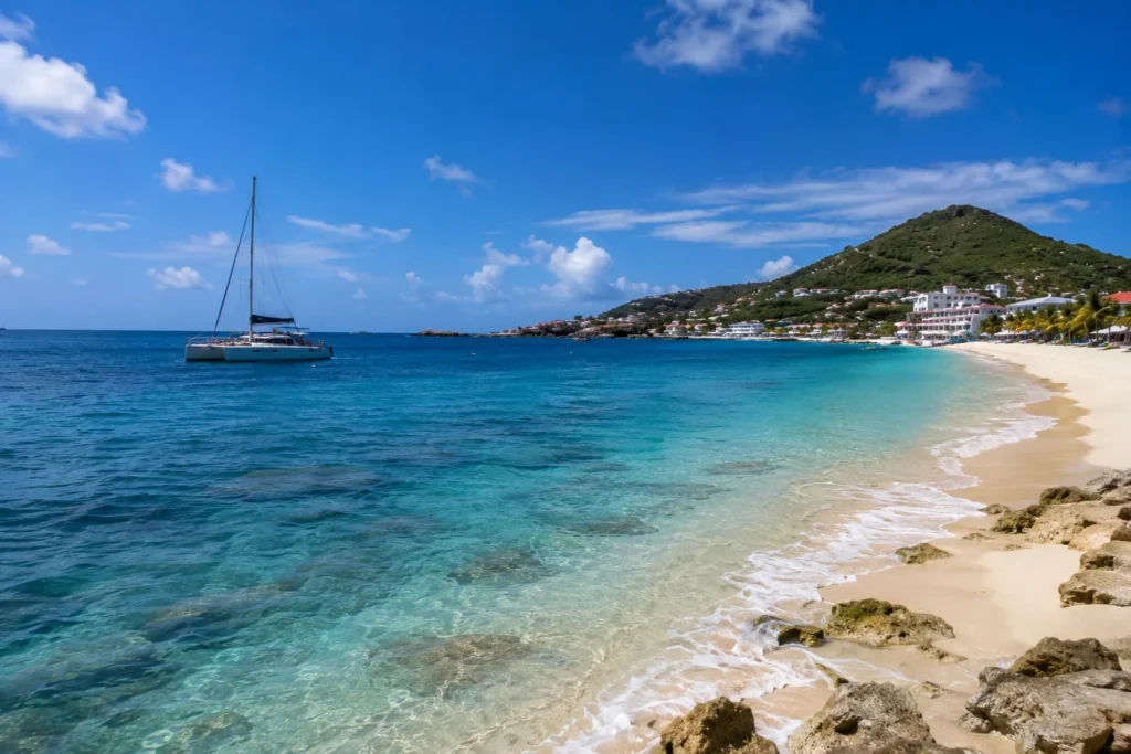 Things to Do in St. Maarten featuring a sandy beach, clear turquoise water, and a sailing catamaran.